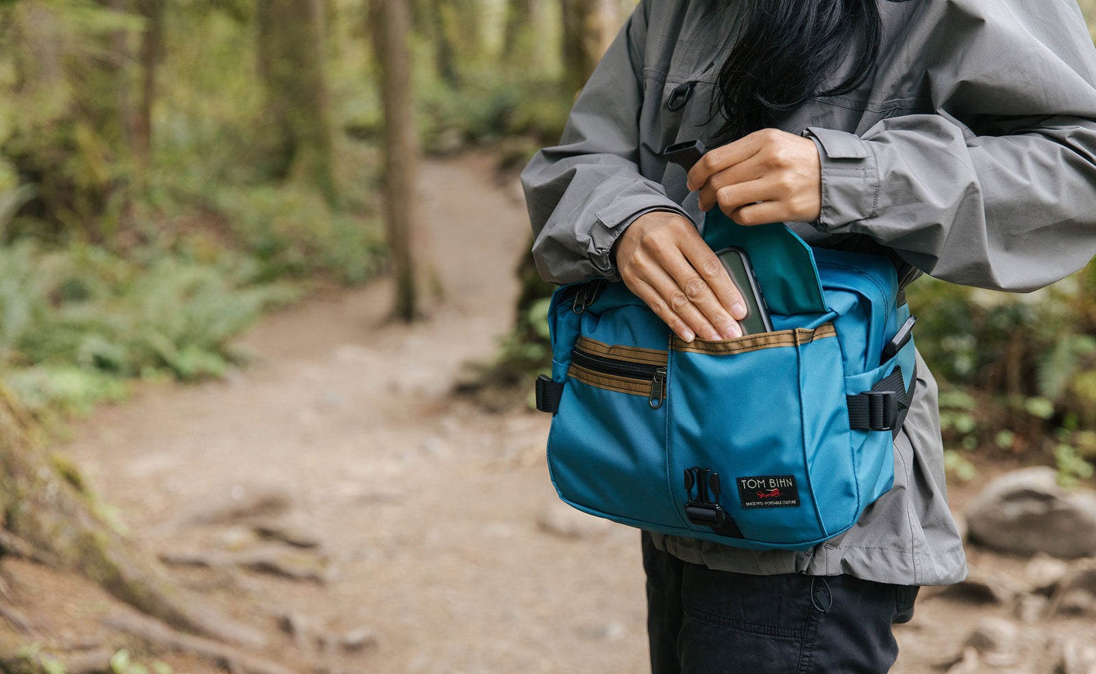 lifestyle visible^^Person accessing a phone from the front buckle pocket of the LGD while wearing it as a waist pack.