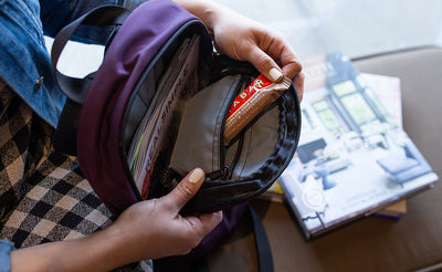 lifestyle visible^^A person retrieving a protein bar from the top zippered pocket in the main pocket.