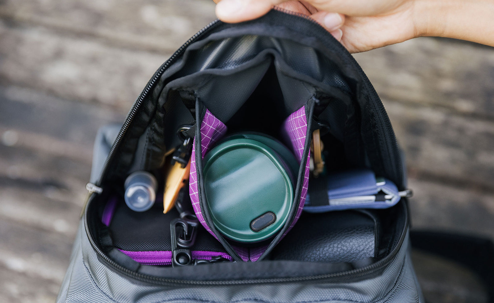 visible lifestyle^^A top-down shot of the Paradigm's front pocket filled with a water bottle, a wallet, keys on a carabiner, a Small Ghost Whale Pouch, some lotion, and hand sanitizer.