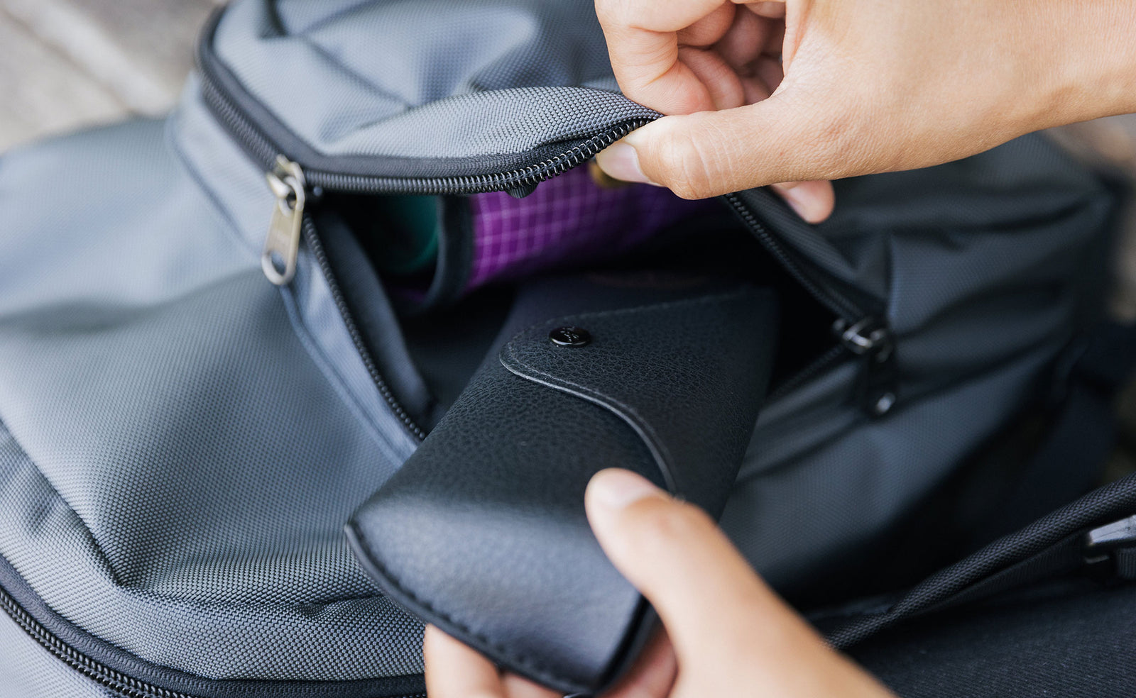 visible lifestyle^^A person retrieving an eyeglasses case from the front pocket of the Paradigm