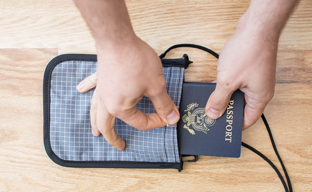 detail visible^^A person removing a US Passport into a Passport Pouch.