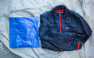 detail visible^^An unfolded Pocket Travel Pillow case and padded jacket.