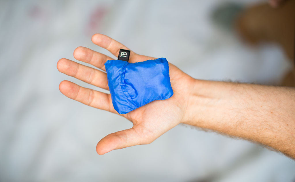 detail visible^^A folded Pocket Travel Pillow in the palm of a person's hand.