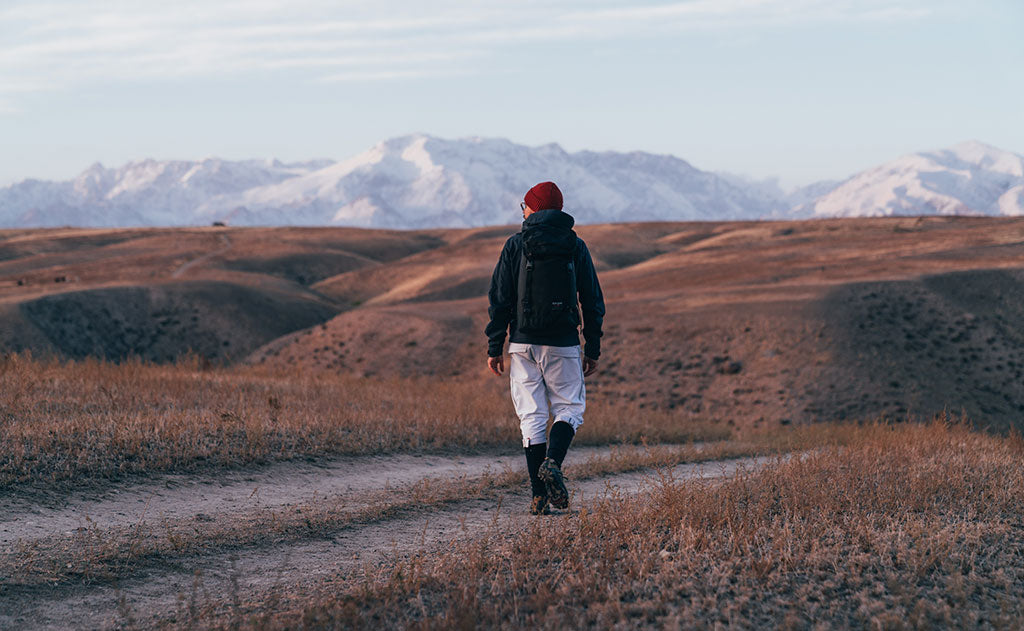 visible lifestyle^^A person carrying the Original Shadow Guide 31 down a dirt road.