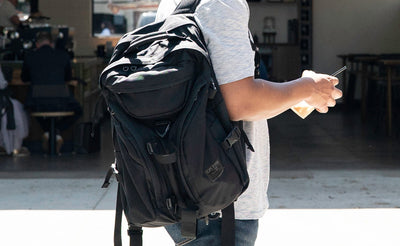 lifestyle visible^^A person wearing a Brain Bag over one shoulder while drinking an iced beverage.