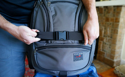 detail visible ^^ A person securing a Synapse to a rolling bag with the Simple Rolling Luggage Strap