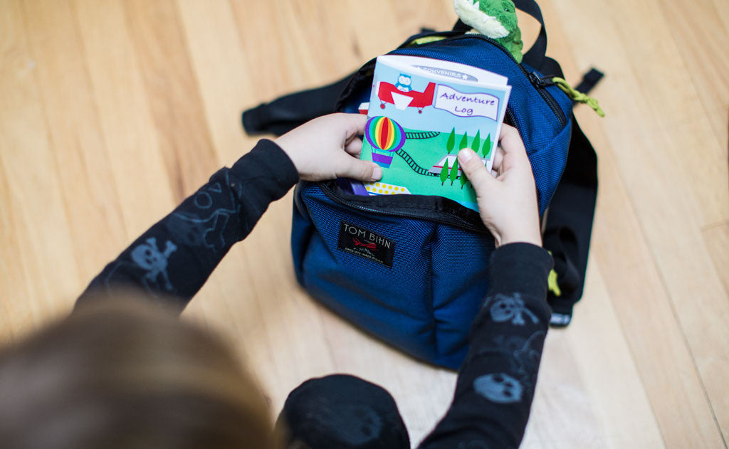 detail visible^^A child removing a book from the main compartment of The Sprout.
