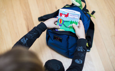 detail visible^^A child removing a book from the main compartment of The Sprout.