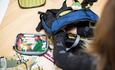 detail visible^^A child connecting their craft pouch to an o-ring in the main pocket of The Sprout.