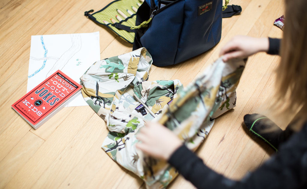 detail visible^^A child folding their jacket, The Sprout waiting patiently next to them.