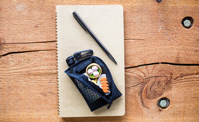 A  open Super Mini Mesh Ghost Whale Pouch on top of a notebook on a table.