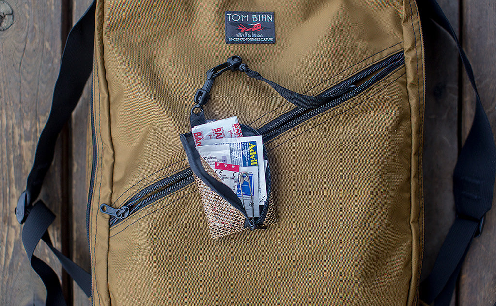 A Super Mini Ghost Whale Pouch full of Band Aids, attached to a Key Strap in a Daylight Backpack.