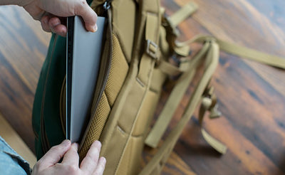 detail visible^^A person putting a laptop into the laptop compartment of the Guide's Edition Synik 22.