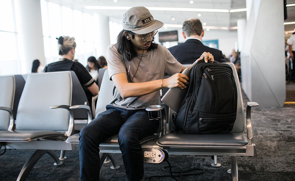 A person pulling their laptop from the Synik 30 at an airport.