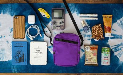 lifestyle visible^^Everyday Cubelet with items around it that will fit inside: snack bar, small drink, doodle kit, phone, mini knife, game boy, phone cord, airpod, make-up, stuffed animal.