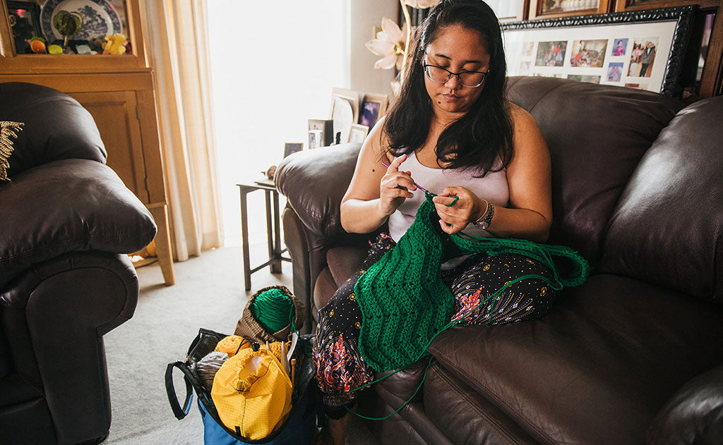 lifestyle visible^^Woman crocheting a blanket while sitting on the couch; with the Truckasana at her feet.