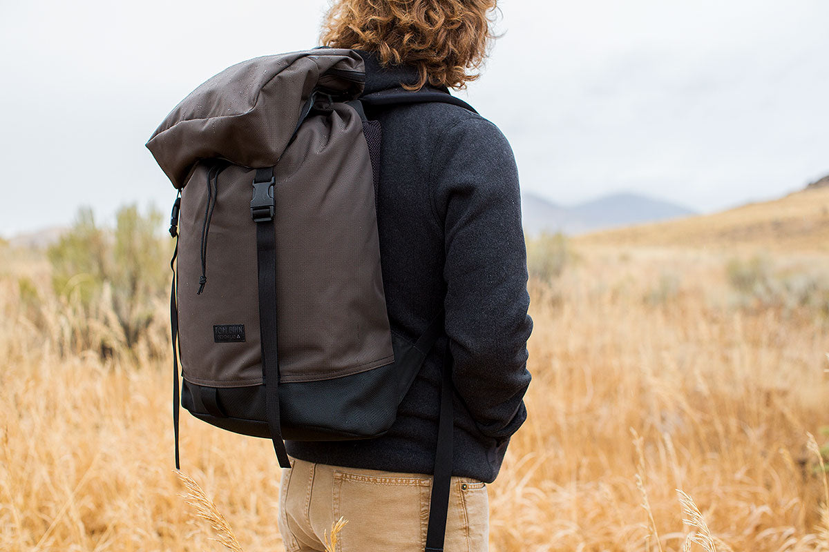 visible variant TB0117-RKLJ^^Man standing in a grassy field wearing the Shadow Guide in Ursa brown.