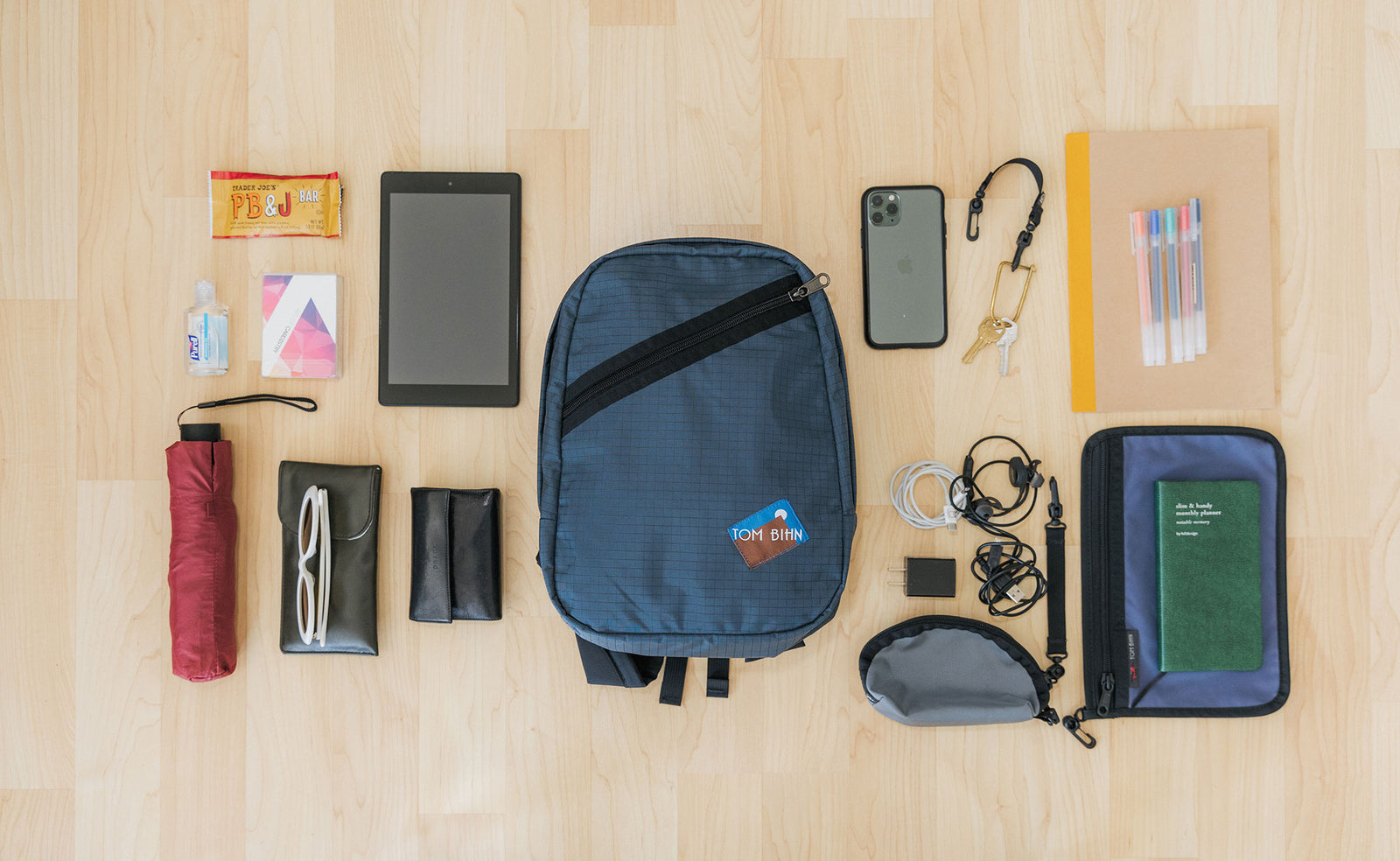 visible lifestyle^^A possible pack for the Zeitgiest, including a retractable umbrella, sunglasses, Small Q-Kit with charge cords, a phone, keys, pens, a tablet, tissues and hand sanitizer, and a small Clear Organizer Pouch with a journal.