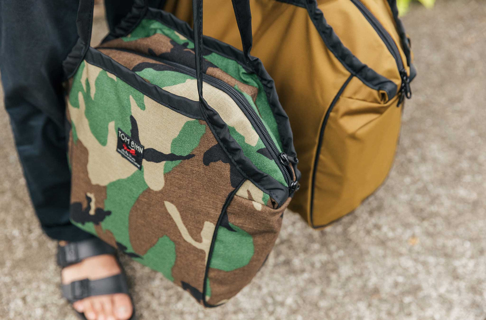 lifestyle visible^^Person standing and carrying the Zip-Top Shop Bag, Size Small, in Beaver Camo.